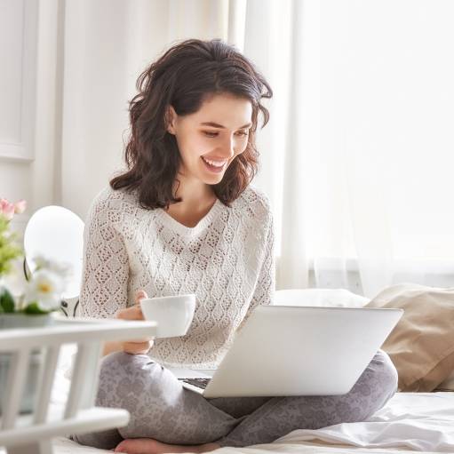 Frau schaut lächeld auf ihren Laptopbildschirm